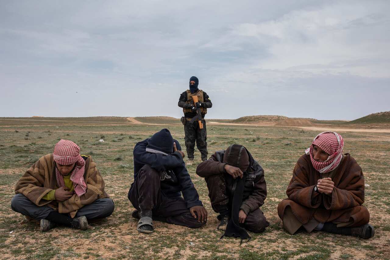 Men who fled the last village held by the Islamic State group wait to be questioned by coalition forces in the province of Deir el-Zour, Syria, on Feb. 7, 2019. (Ivor Prickett/The New York Times)