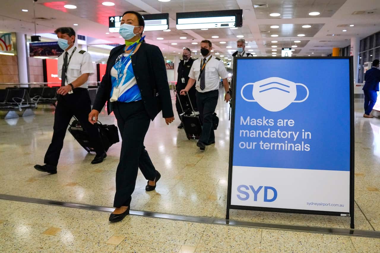 A flight crew walk through the terminal at Sydney Airport, Monday, Nov. 29, 2021. Authorities in Australia said Sunday, Nov. 28, 2021, that two travelers who arrived in Sydney from Africa became the first in the country to test positive for the new varian