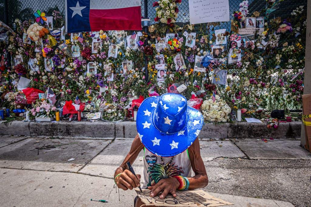 A person writes a message on the 4th of July at a memorial for those missing after the partial collapse of the Champlain Towers South condo building in Florida.
