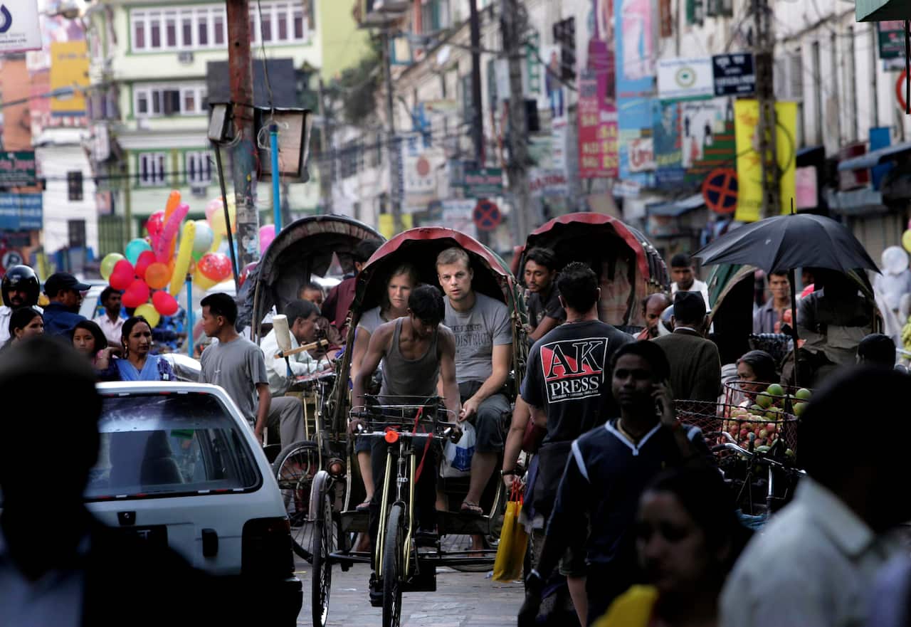 Foreign tourists ride a rickshaw, in Kathmandu, Nepal.