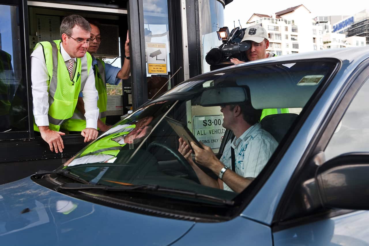 Supplied photo of Roads Minister Michael Daley presenting an RTA electronic toll tag to the last driver to pay for his toll in cash on the Sydney Harbour Bridge, Sunday, Jan. 11, 2009. After more than 75 years, cash toll boothes on the bridge were closed