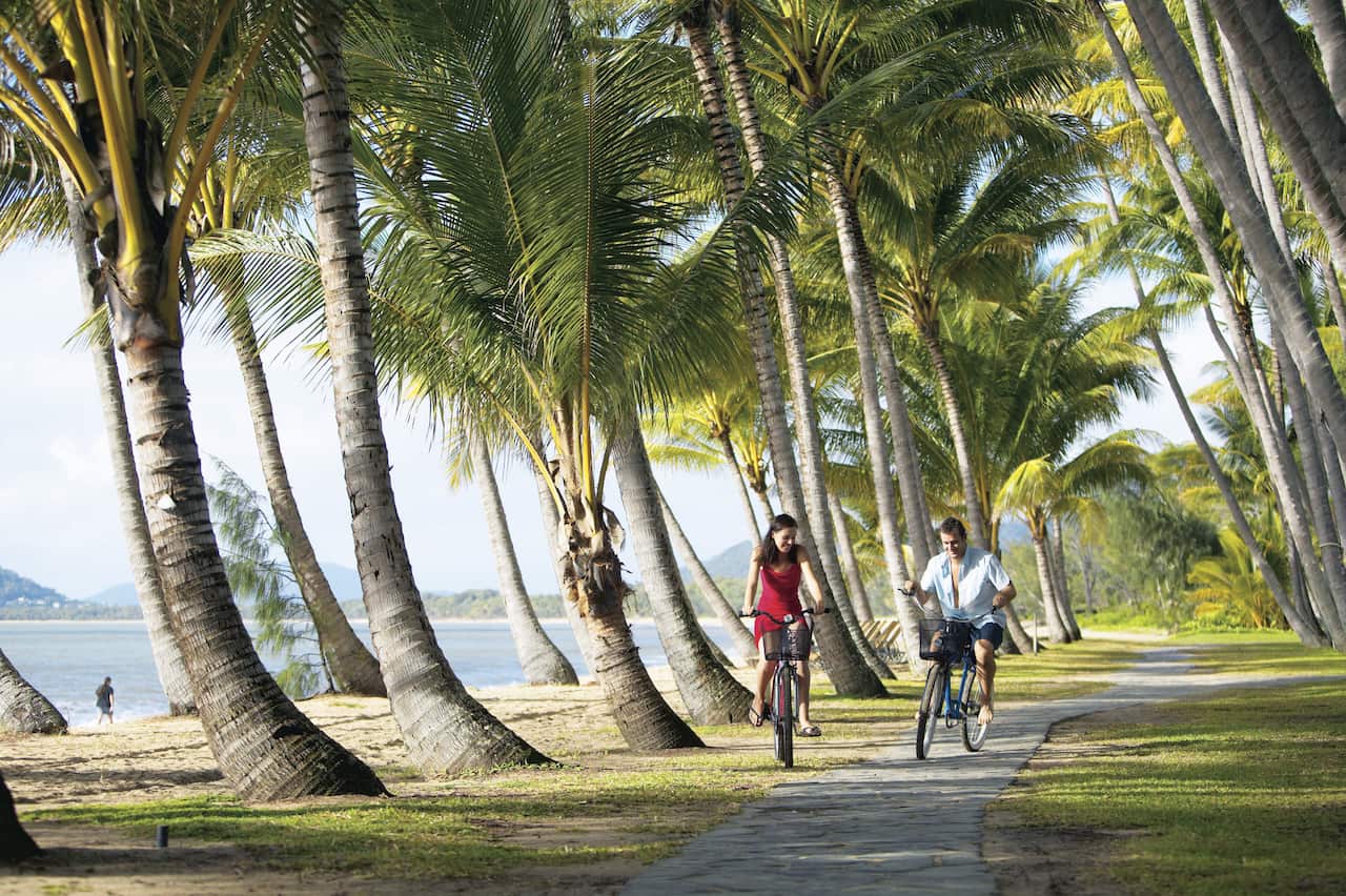 An undated supplied photo of a couple bicycling near the beach at Palm Cove in far north Queensland. Palm Cove is being marketed as a romantic retreat. (AAP Image/Tourism Queensland) NO ARCHIVING EDITORIAL USE ONLY