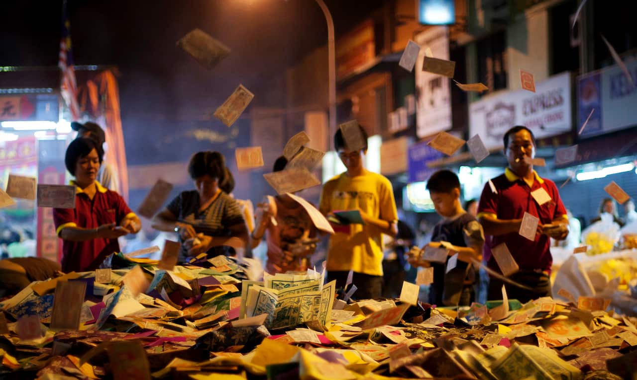 People throw 'hell money' for burning as part of the festival.