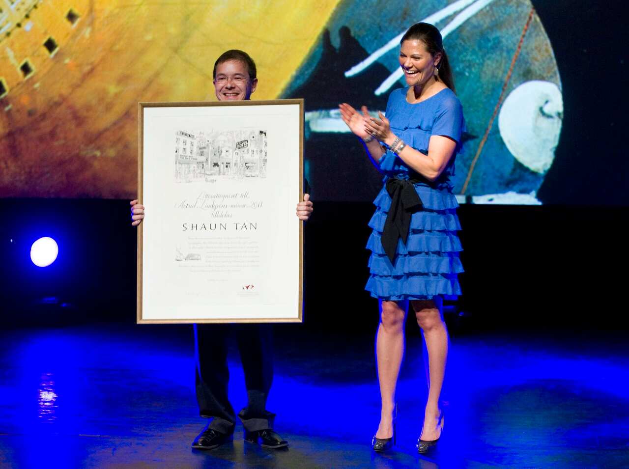 Australian child book illustrator Shaun Tan (L) holds up the Astrid Lindgren Memorial Award after receiving it from Swedish Crown Princess Victoria (R) during a ceremony at the Stockholm Concert Hall in Sweden, 31 May 2011.