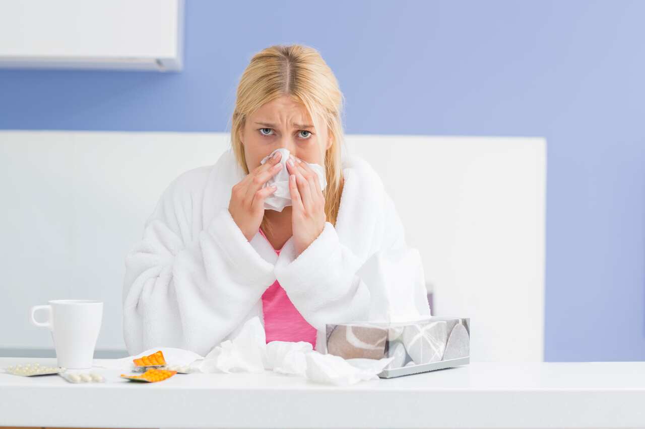 Portrait of young woman blowing nose in tissue paper