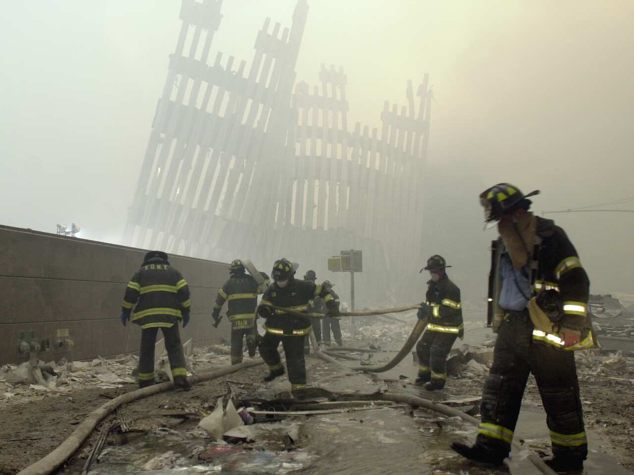 Firefighters work beneath the destroyed mullions, the vertical struts which once faced the soaring outer walls of the World Trade Center