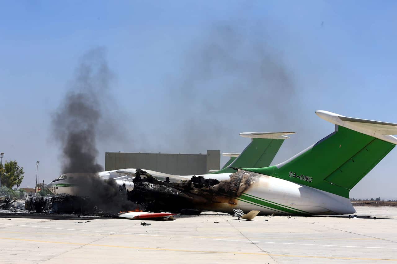 damaged planes and smoke rises following clashes between rival militias at the main airport of Tripoli, Libya, 16 July 2014. 