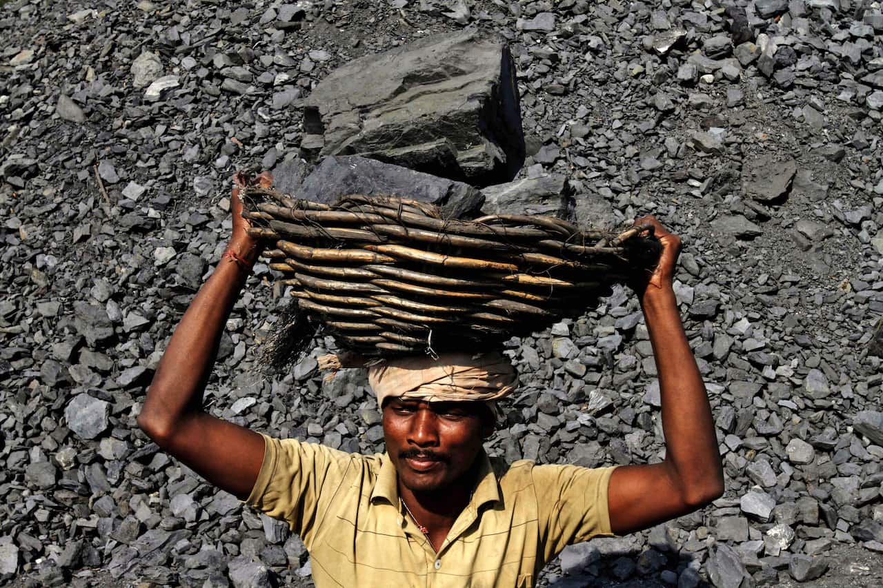 In this Thursday, Nov. 13, 2014 photo, an Indian daily wage laborer carries a basket on his head filled with chunks of coal at a local coal depot on the outskirts of Cuttack, 25 kilometers (16 miles) from the eastern Indian city of Bhubaneswar. This week'