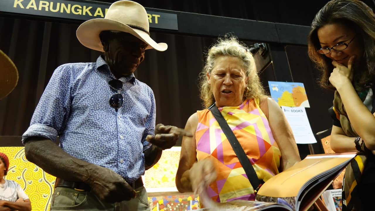  Jimmy Wavehill explains the historic Wave Hill Station walk-off of 1966 to Catherine Croll and Chinese art curator Fan Lin at the Darwin Aboriginal Art Fair
