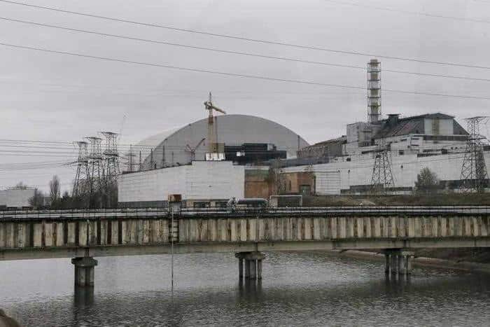 The old sarcophagus, right, over the reactor building damaged by explosion and a new confinement, left, under construction at the Chernobyl nuclear power plant. (AAP)