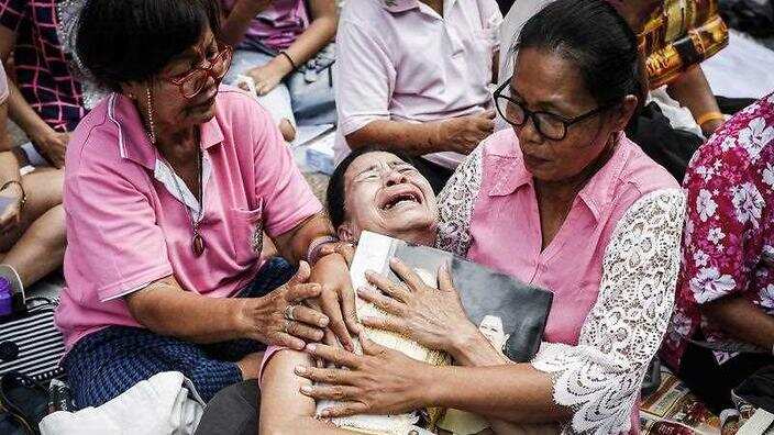  A Thai well-wisher weeps as she is comforted by others during a prayer for Thai King Bhumibol Adulyadej. (AAP) 