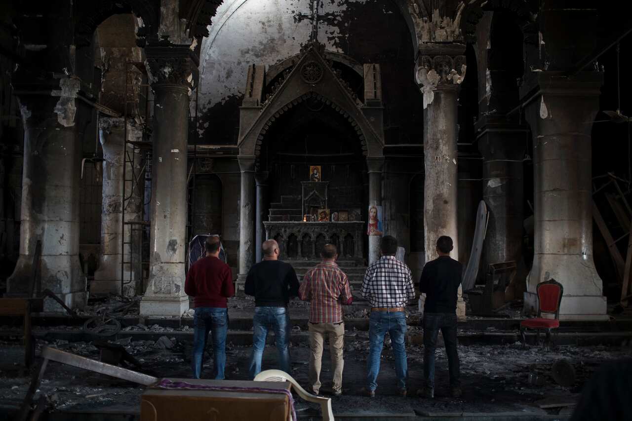 Iraqi Christians pray at the Church of the Immaculate Conception, damaged by Islamic State fighters during their occupation of Qaraqosh, east of Mosul