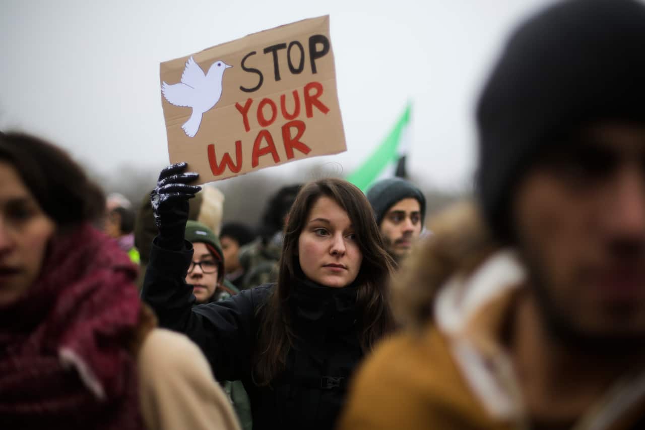 A woman holds a poster as she attends a demonstration against the ongoing war in Syria and the humanitarian crisis in besieged Aleppo  in front of the Reichstag Parliament building in Berlin, Saturday, Dec. 17, 2016. (AP Photo/Markus Schreiber)