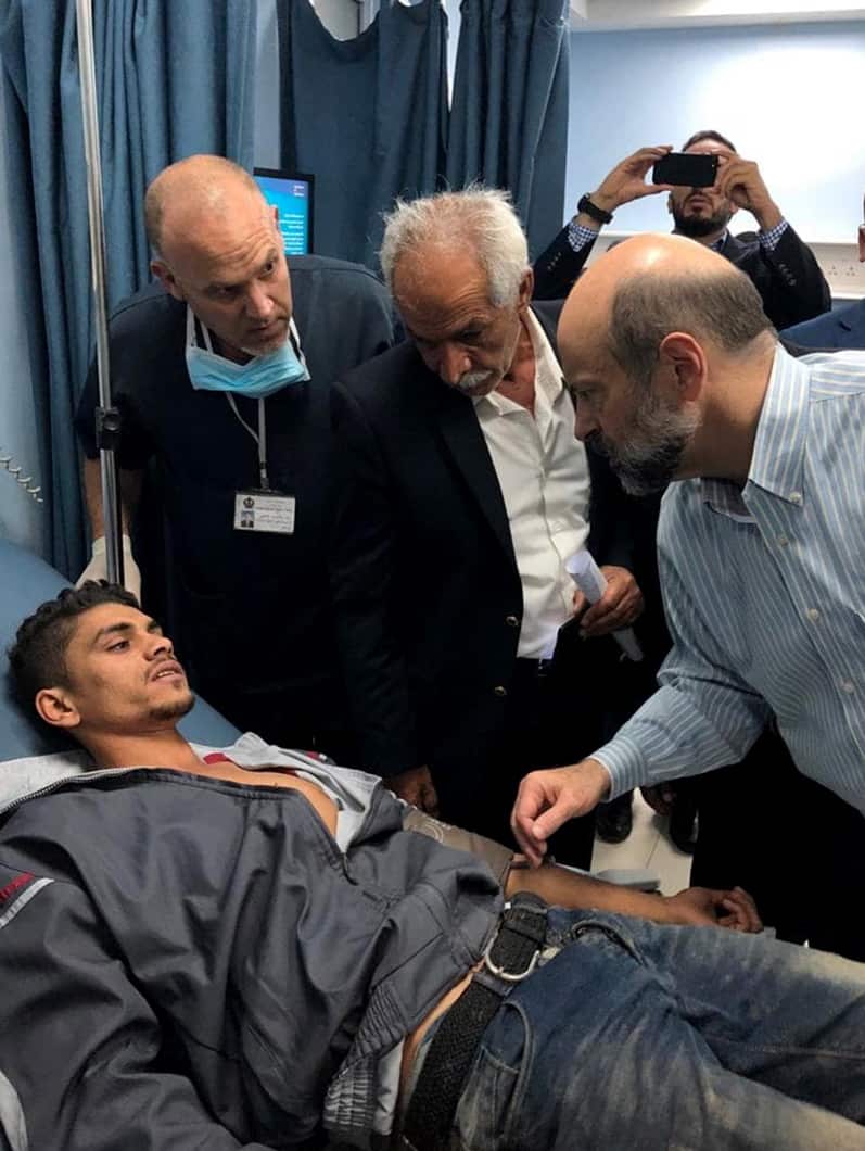 Prime Minister Omar al-Razzaz (R) visiting people injured after a school bus was swept away by torrential rain, at an identified hospital, Jordan,
