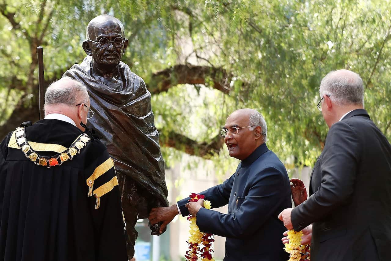 Indian President Ram Nath Kovind, center, places flowers on a Gandhi statue as Australian Prime Minister Scott Morrison, right, watches in Parramatta.