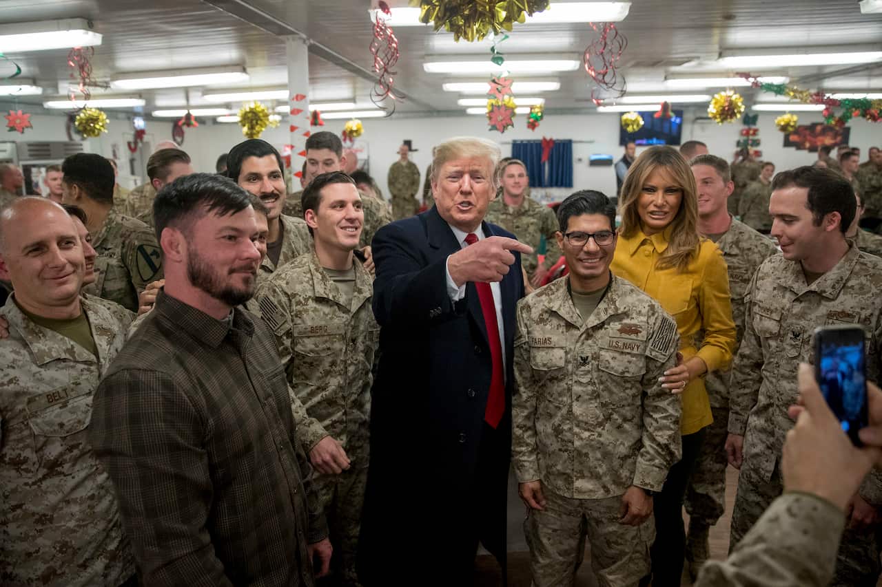 President Donald Trump and first lady Melania Trump pose for a photograph as they visit with members of the military at a dining hall at Al Asad Air Base