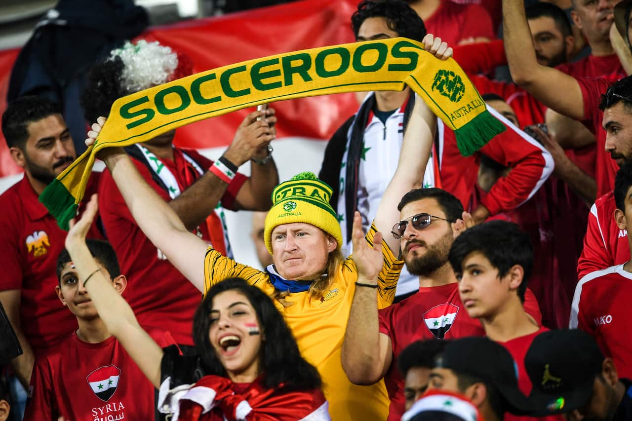 An Australian fan, center, shows a slogan to show support for Australia national soccer team