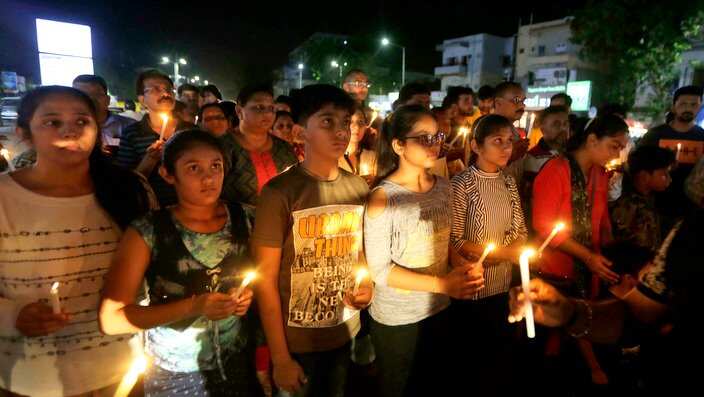 Indians holds candles during a candle march to pay tribute to the victims of deadly fire in Surat, in Ahmadabad, India. 