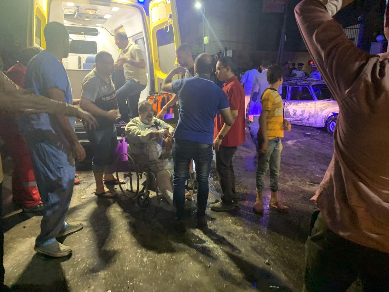 People tend to an injured man after a blast at the National Cancer Institute, Cairo, Egypt