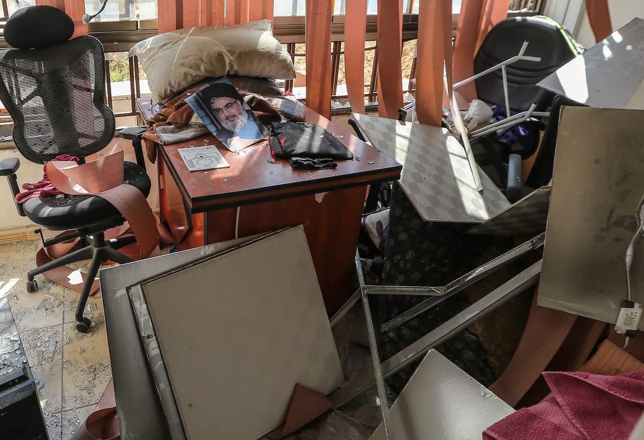 A photograph depicting Hezbollah leader Hassan Nasrallah lies amid damaged items inside the Hezbollah media office in the southern suburb of Beirut