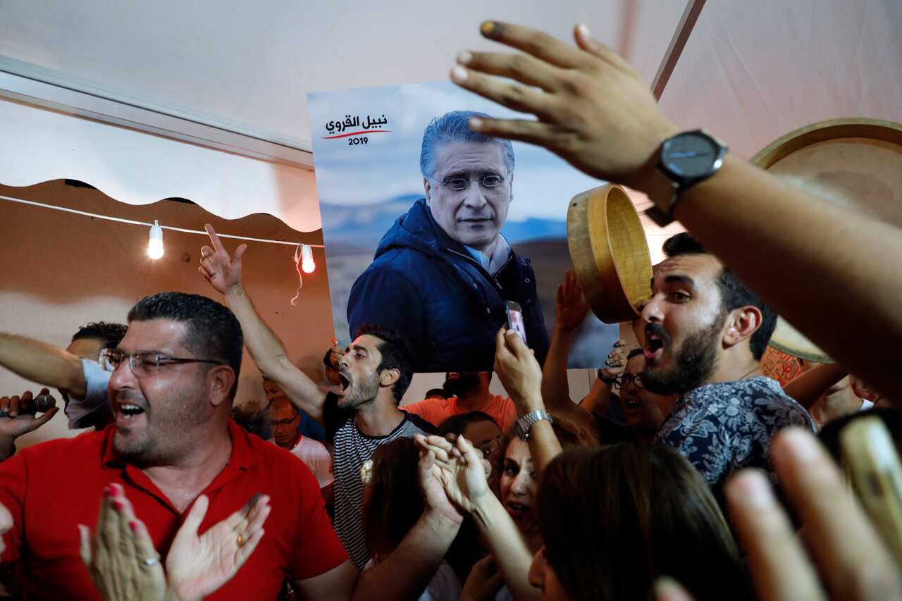 Supporters of Tunisia's jailed presidential candidate Nabil Karoui celebrate in front of his headquarters as results come in