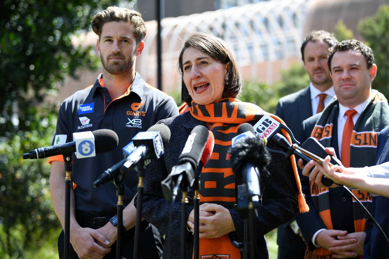 Callan Ward of the GWS Giants looks on as NSW Premier Gladys Berejiklian speaks to the media at Parliament House in Sydney