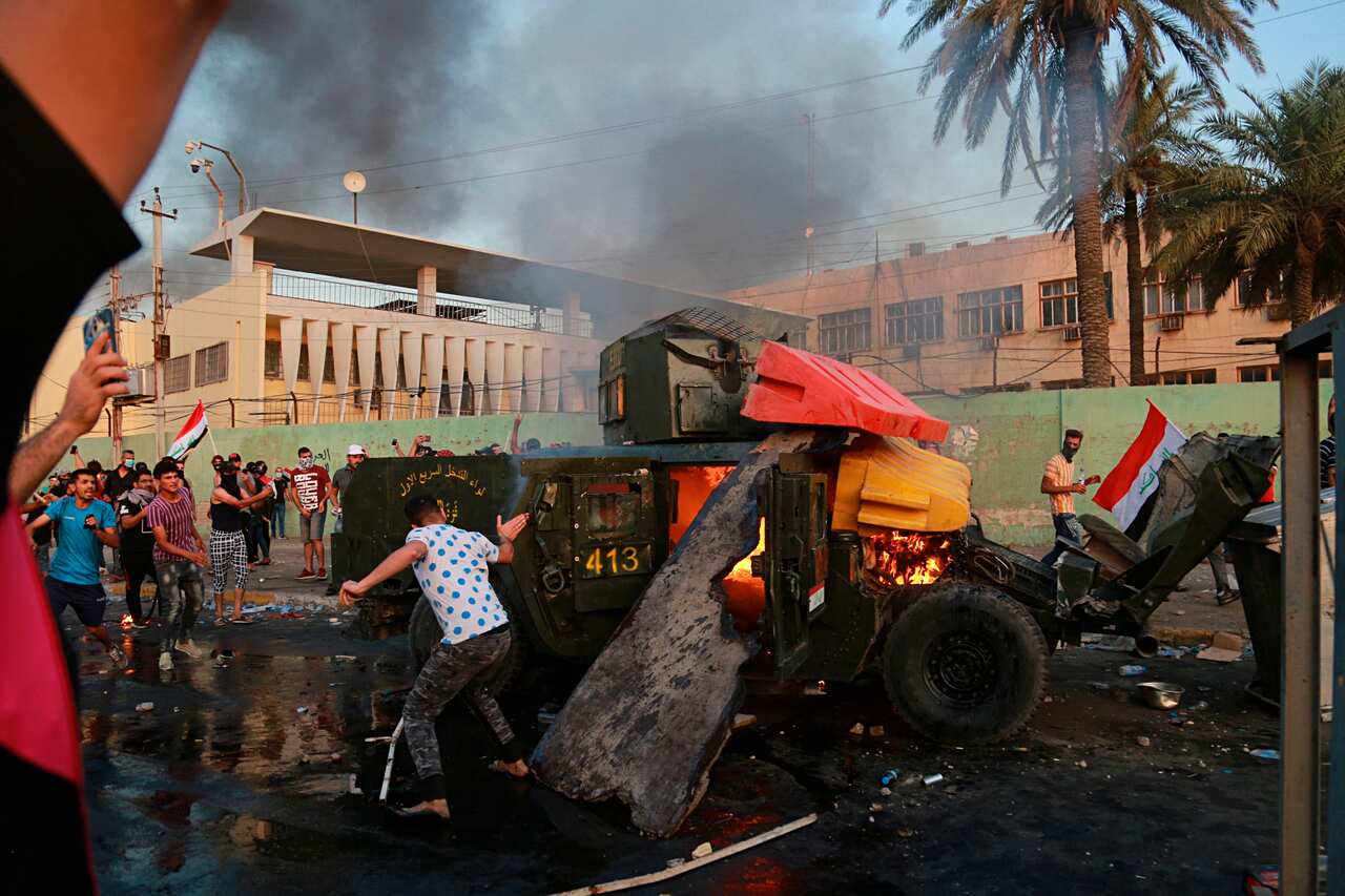 Anti-government protesters burn an armored vehicle belonging to the Federal Police Rapid Response Forces during a protest in Baghdad