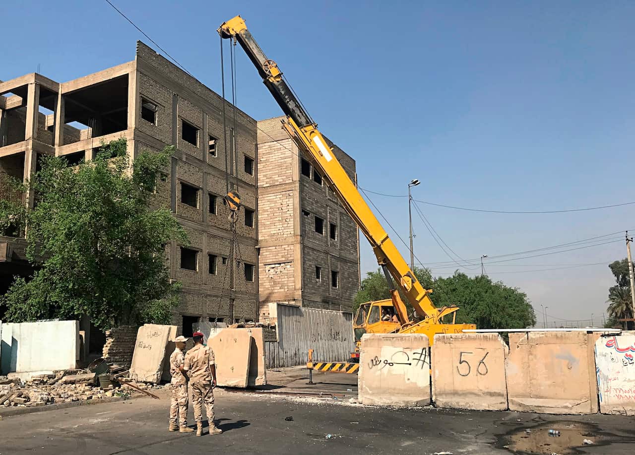 Iraqi security forces remove concrete blast walls that were cutting the streets in the protest site area of Baghdad, a day after calmness was restored in the Iraqi capital, Tuesday, Oct. 8, 2019. (AP Photo/Ali Abdul Hassan)