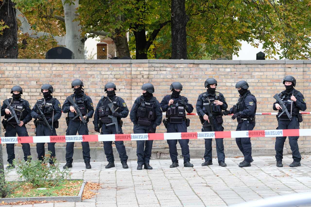 Police officers with helmets secure the area at the Jewish cemetery near the scene, where two people were shot dead in the eastern German city of Halle
