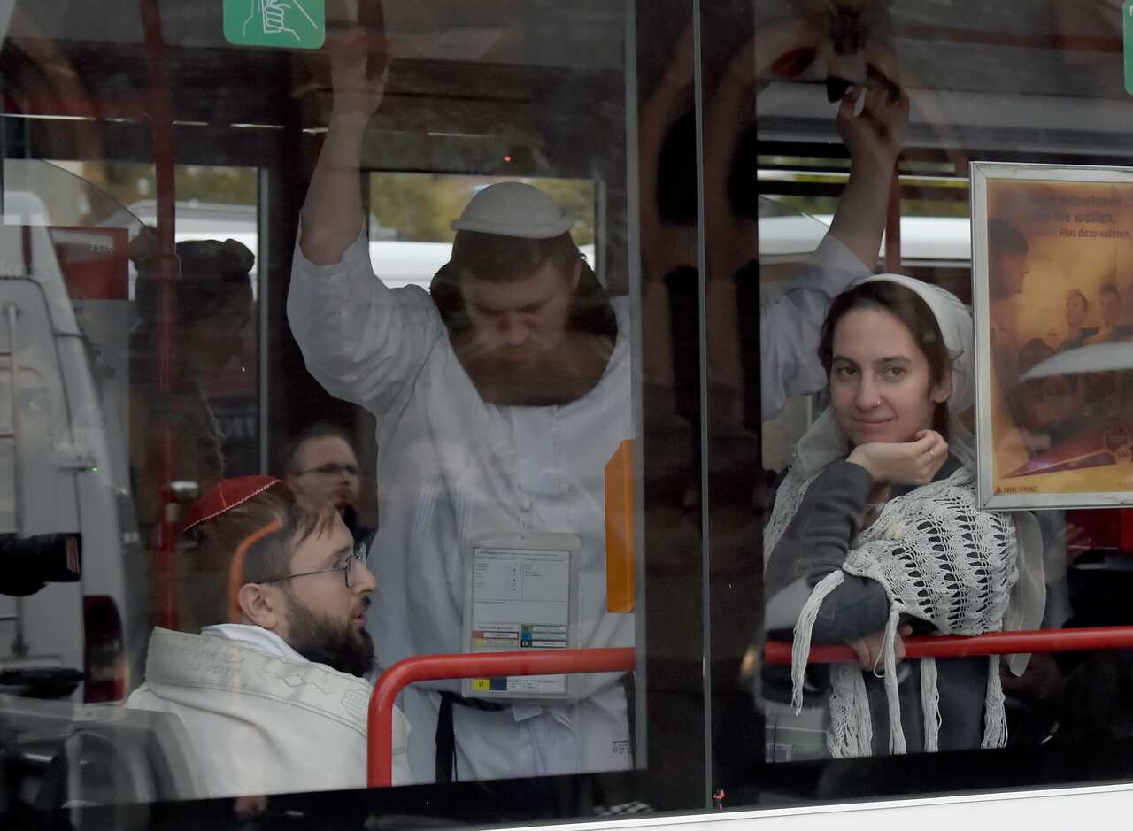 People, wearing traditional Jewish clothing, stay and sit in a bus at a Jewish cemetery and synagogue in Halle, Germany