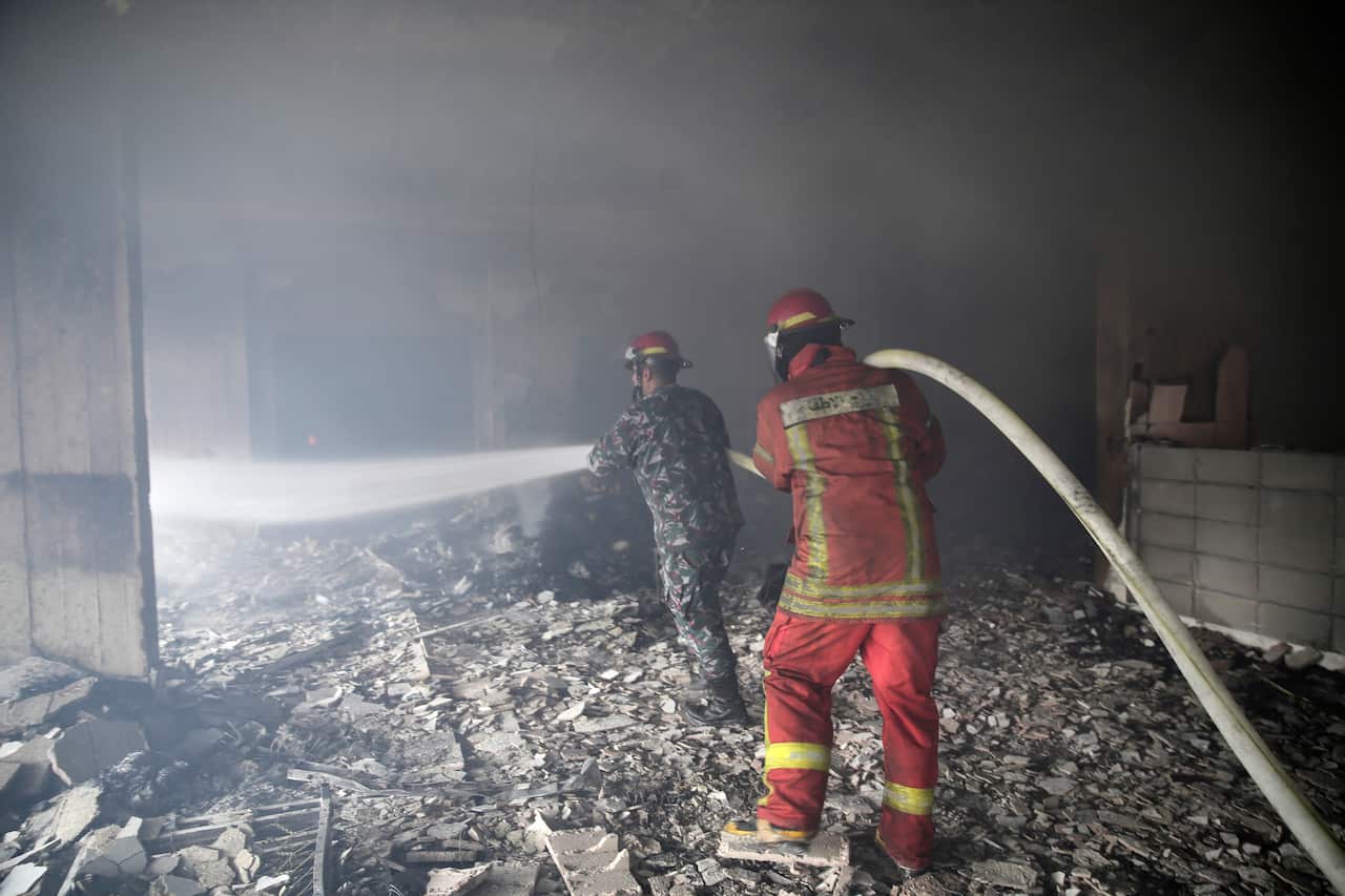 Lebanese firemen extinguish a fire inside a building that was burned in a wildfire overnight, in the town of Damour 
