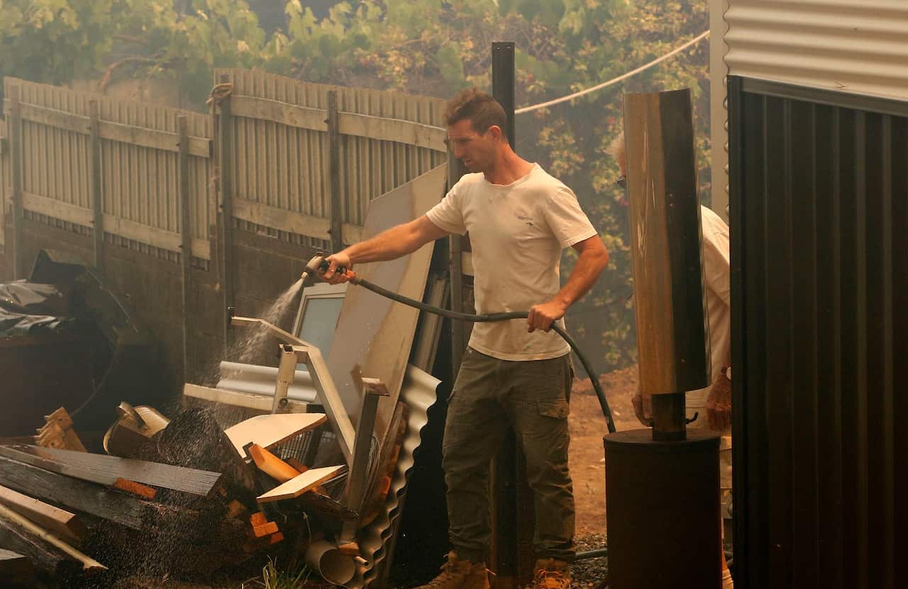 A resident prepares for the approaching bushfire at Old Bar, NSW, Saturday, November 9, 2019. (AAP Image/Darren Pateman)