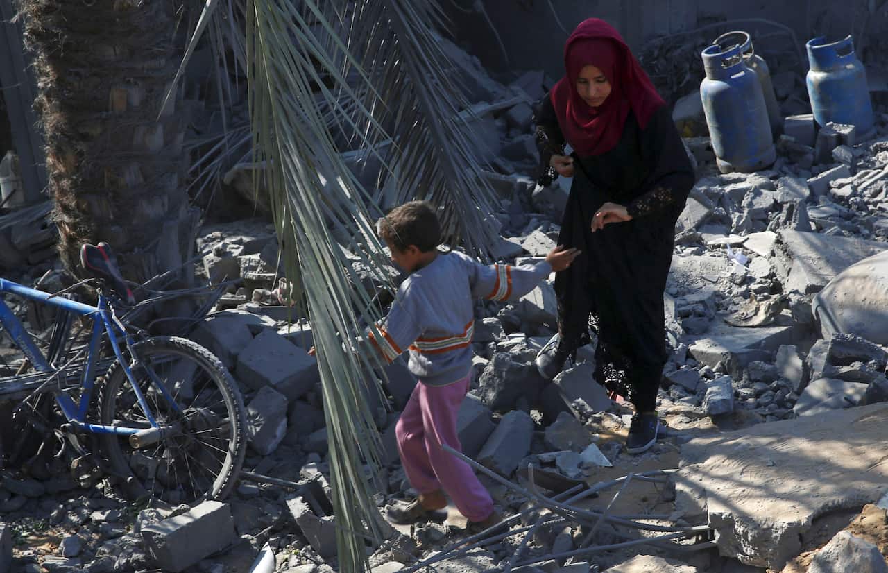 Palestinians walk amid the rubble of their family house following overnight Israeli missile strikes, in Al-Qarara, east of Khan Younis, southern Gaza Strip, Thursday, Nov. 14, 2019. (AP Photo/Adel Hana)