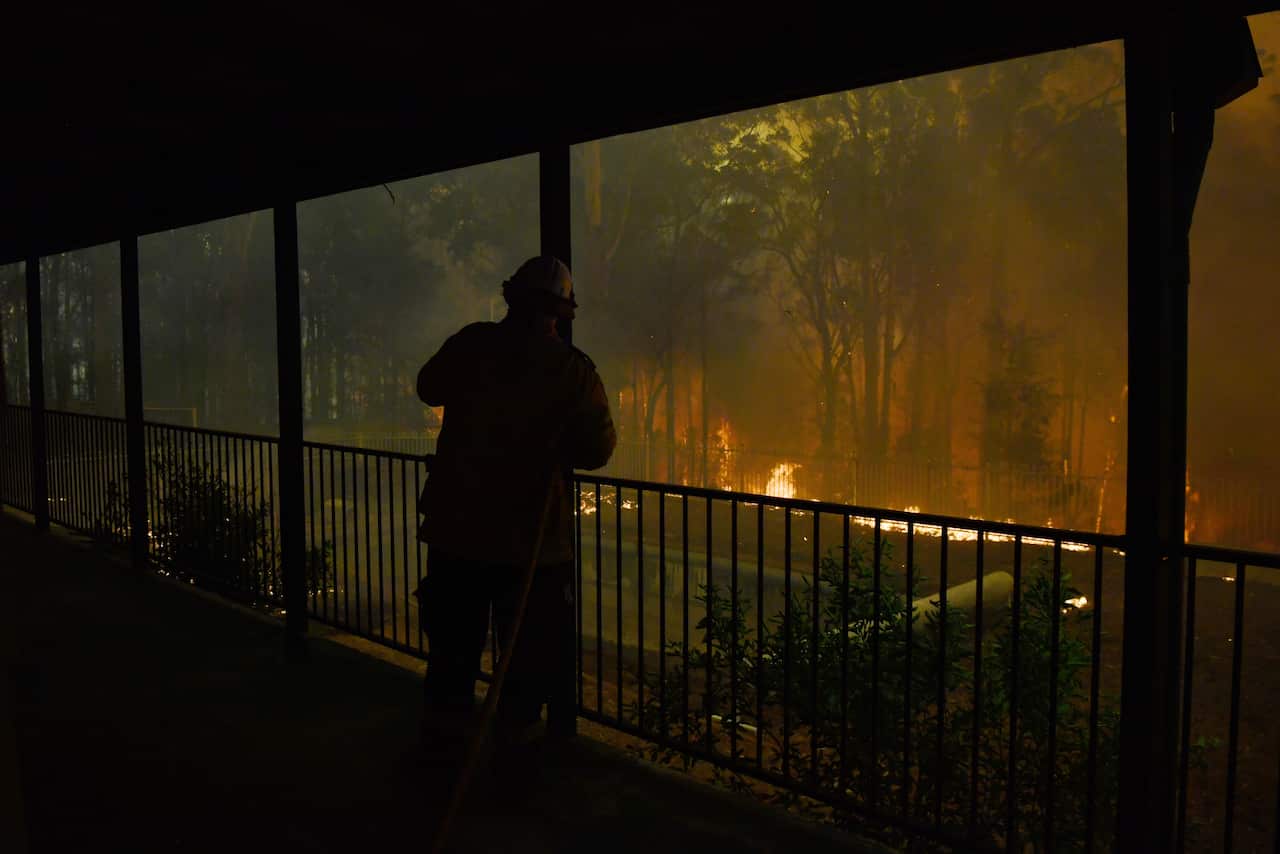 RFS volunteers and NSW Fire and Rescue officers protect a home on Wheelbarrow Ridge Road