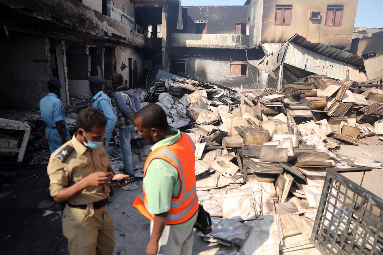 Soldiers and people inspect the site of a tile manufacturing unit after an explosion in an industrial zone, north Khartoum, Sudan