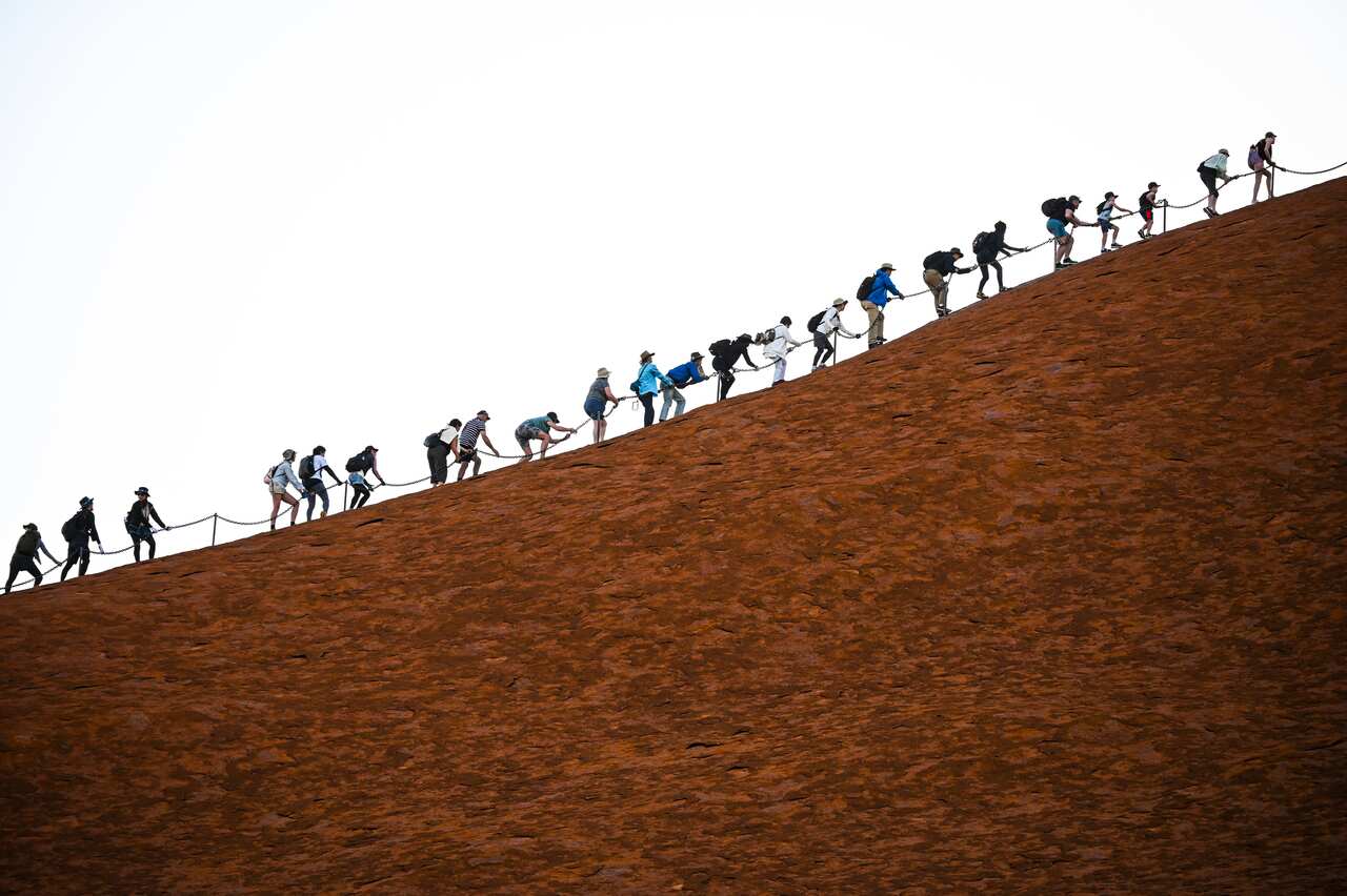 A picture part of a series taken over the past 2 weeks shows a line of tourists climbing Uluru, Friday, October 11, 2019. 
