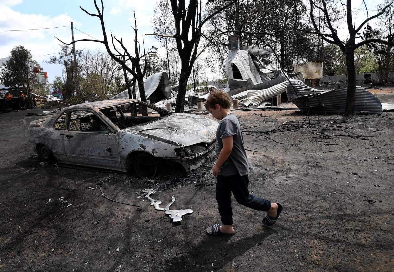 Eight year-old Jarrod McInnes walks next to the remains of a house that his family was about to buy and was destroyed by bushfires in Rappville, NSW 