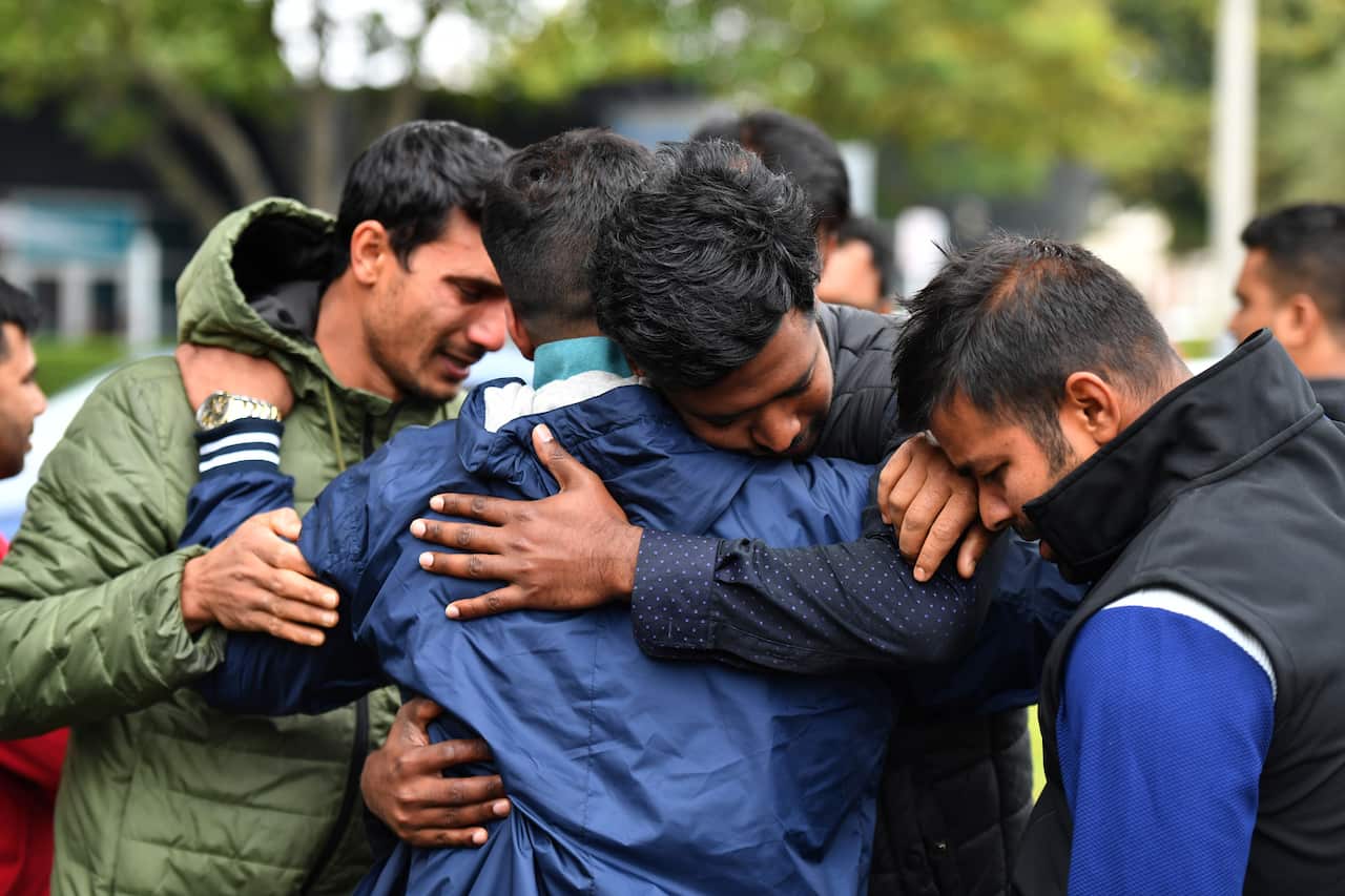 Friends of a missing man grieve outside a refuge centre in Christchurch, Sunday, March 17, 2019.