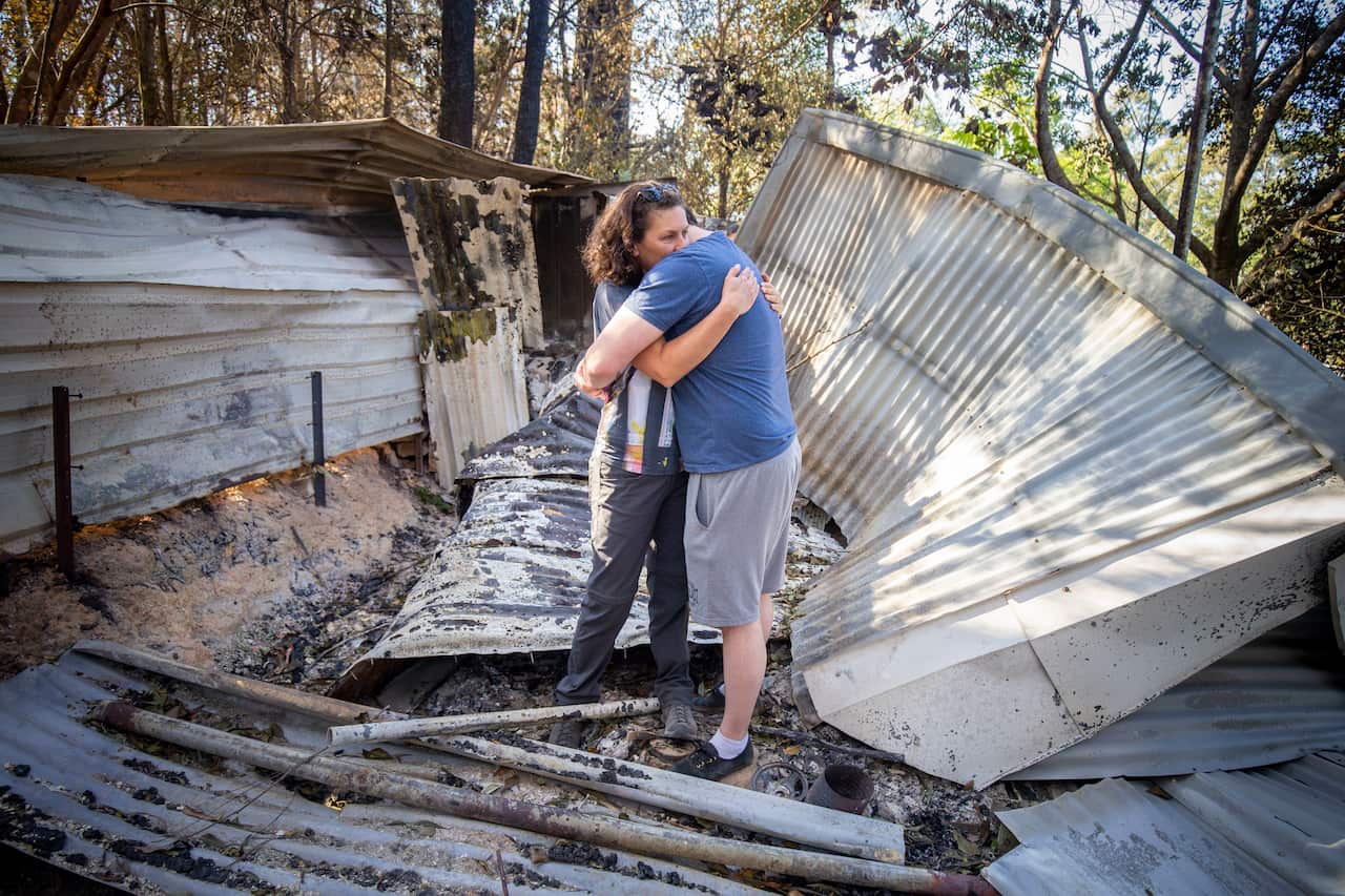 Lisa Groom and her son Luke Beyer stand in the wreckage of a shed on their property on Binna Burra Road, Beechmont 