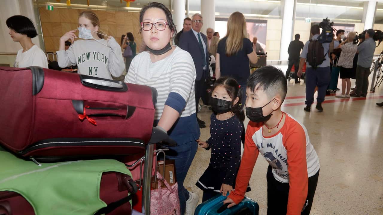 A woman and her children, wearing face masks, arrive in Sydney, Australia, Thursday, Jan. 23, 2020, from a flight from Wuhan, China. China closed off a city of more than 11 million people as part of a radical effort to prevent the spread of a deadly virus