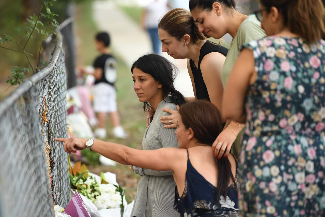 Leila Geagea poses near flowers placed at the scene where seven children where hit on a footpath by a four-wheel drive in the Sydney suburb of Oatlands
