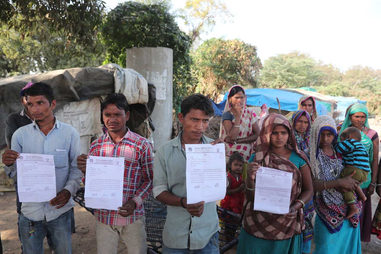 Indian residents of a slum near the stadium hold eviction notices served to them Feb 18, 2020.