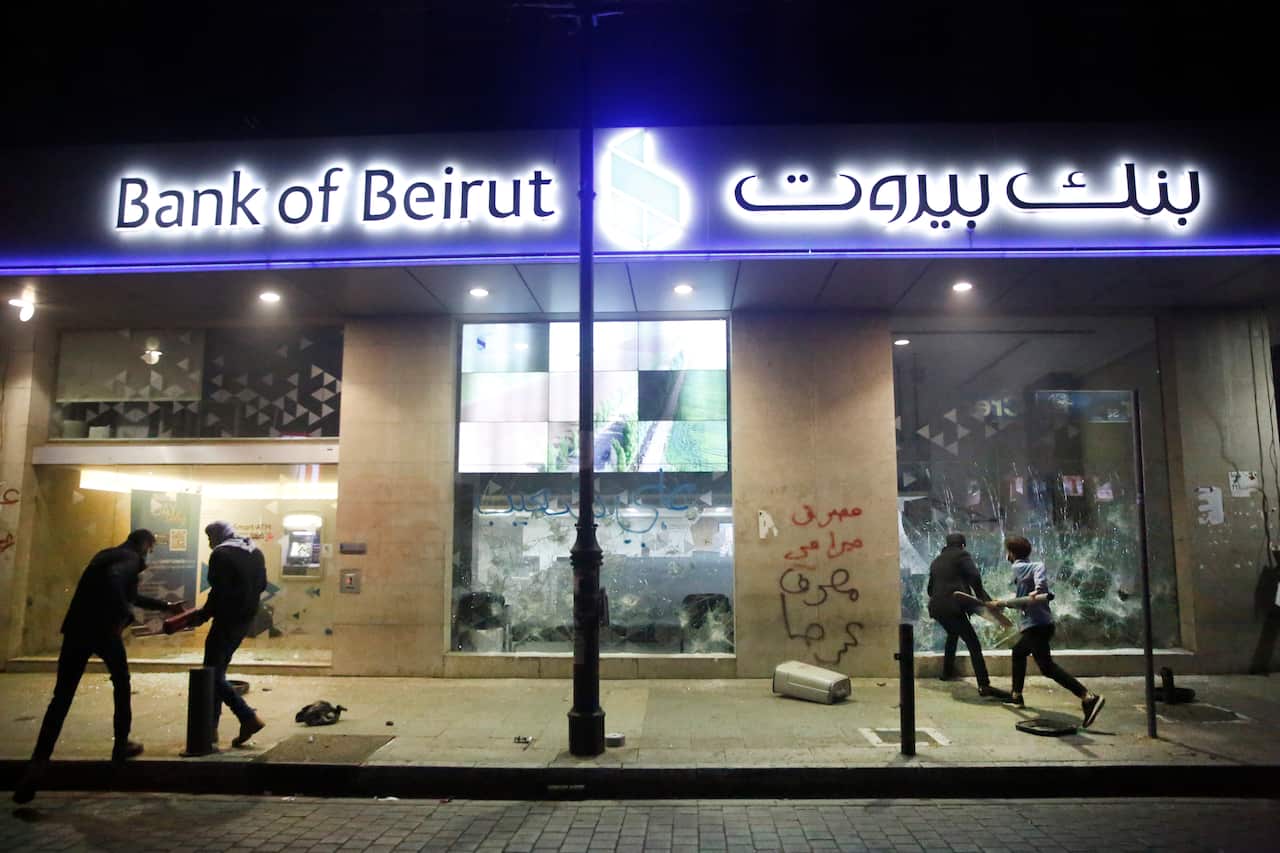 anti-government protesters smash bank widows, during ongoing protests against the Lebanese central bank's governor, on Hamra Street, in Beirut