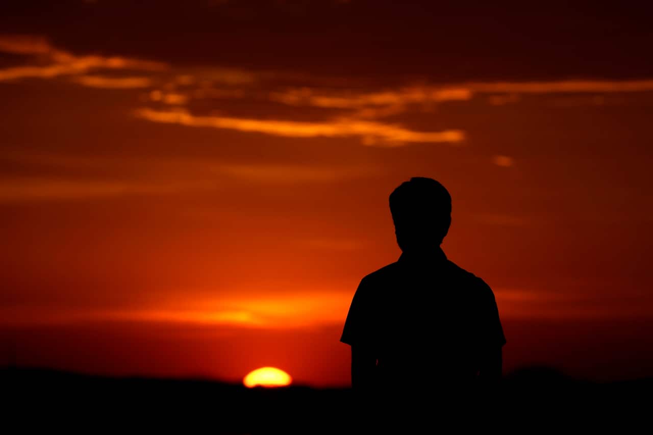 A man watches the sunset in Kansas City, Mo., Saturday, March 7, 2020. Daylight saving time starts Sunday in most states in the U.S. as clocks are advanced by one hour from 2 a.m. local time to 3 a.m. (AP Photo/Charlie Riedel)