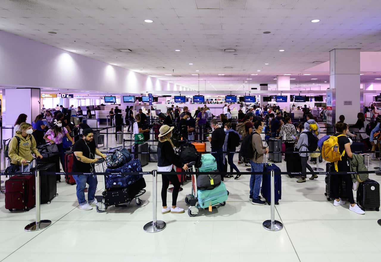 Travellers adhere to social distancing rules as they check in for their flights at the Sydney International Airport, Sydney, Friday, March 27, 2020. 