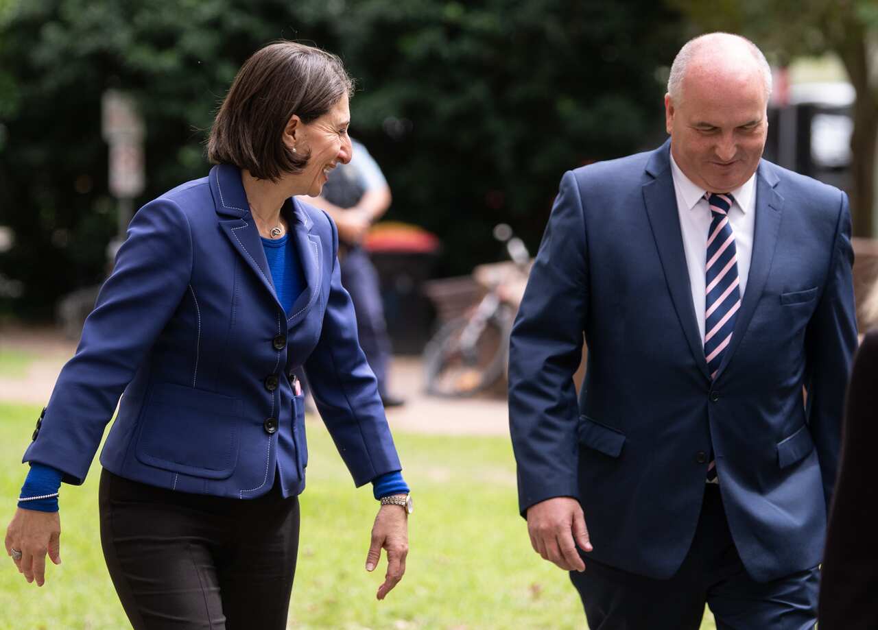 NSW Premier Gladys Berejiklian speaking with NSW Minister for Police David Elliot as they leave a press conference to provide an update on the COVID-19 pandemic in NSW, Sydney, Saturday, March 28, 2020. (AAP Image/James Gourley) NO ARCHIVING