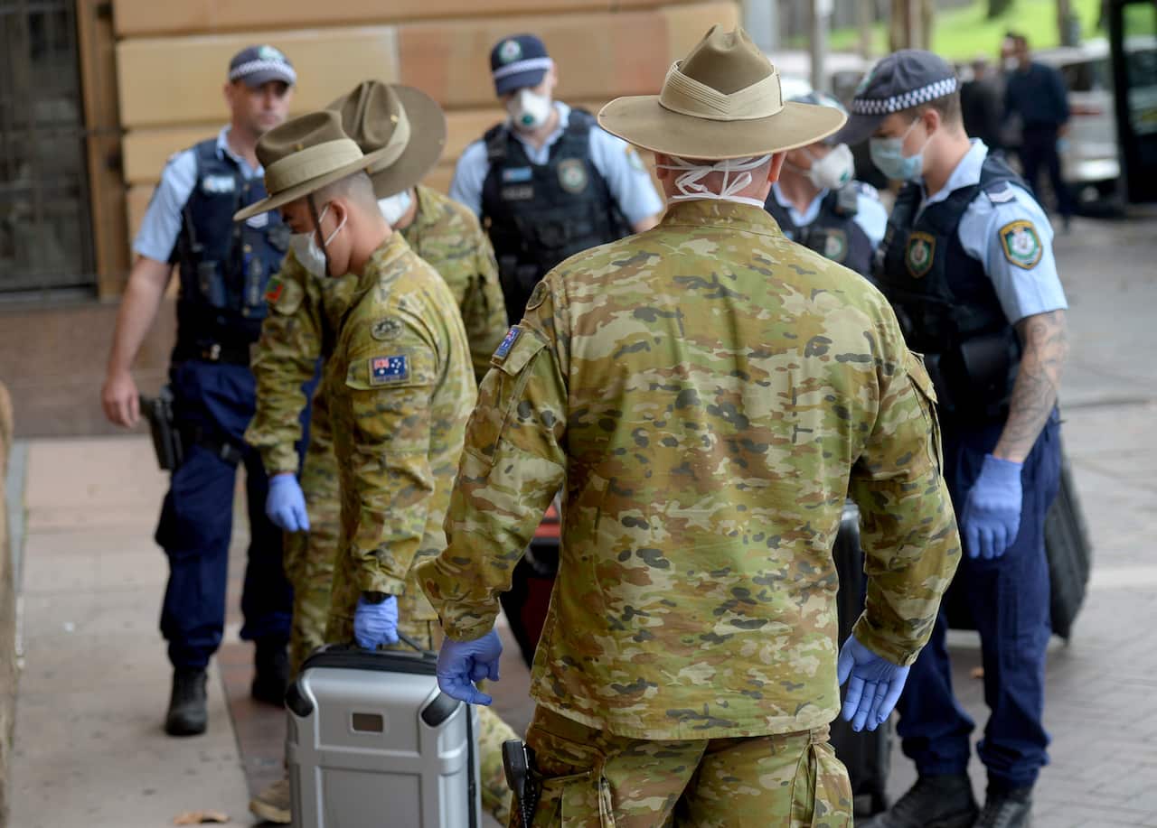 Returning overseas travellers are ushered into the InterContinental Hotel for the beginning of their 14-day imposed quarantine in Sydney, Sunday, March 29, 2020. (AAP Image/Jeremy Piper) NO ARCHIVING