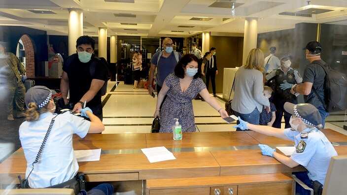 Returning overseas travellers are ushered into the InterContinental Hotel for the beginning of their 14-day imposed quarantine in Sydney, Sunday, March 29, 2020. (AAP Image/Jeremy Piper) NO ARCHIVING
