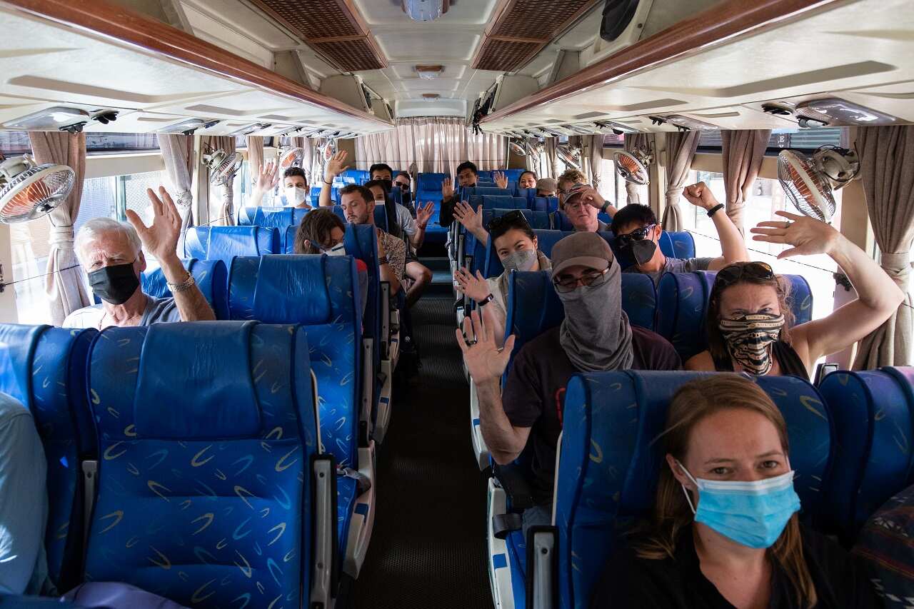 Stranded Australian citizens wave to journalists as they get ready to move to Tribhuvan International Airport during the ninth day of the nationwide lockdown.