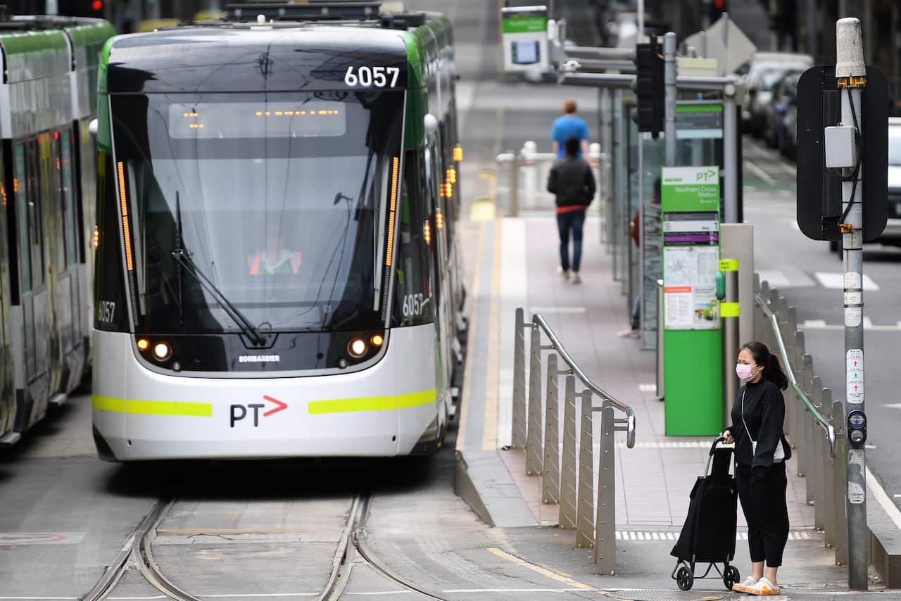 People wearing face masks as a preventive measure against Coronavirus are seen after disembarking a tram in Melbourne, Monday, April 6, 2020. Stage three social distancing measures are now in force throughout Victoria. (AAP Image/James Ross) NO ARCHIVING